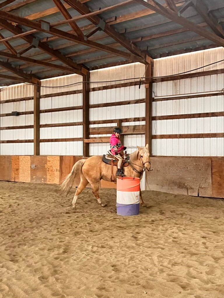 Child riding a palomino horse inside the indoor arena at Kiesling Acres in Valleyford, Washington.